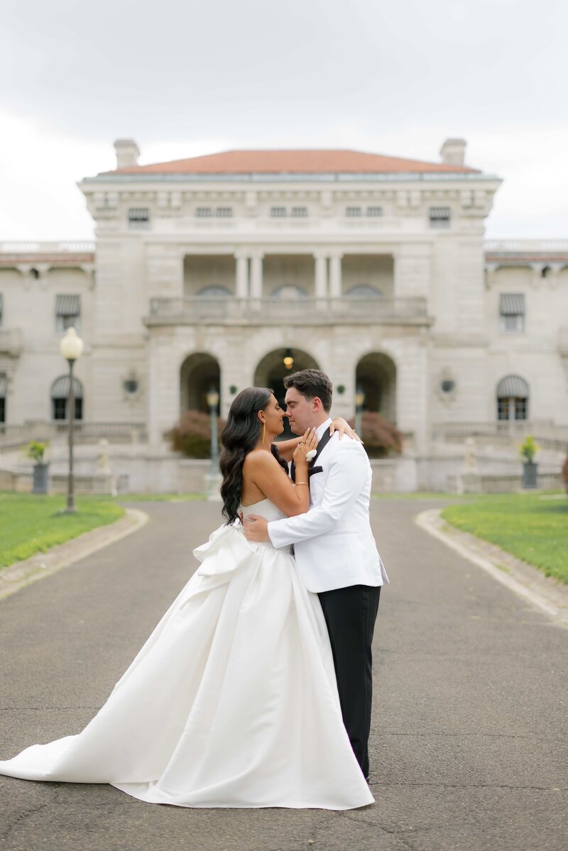 Jaimi and Ryan, a Heather Paperie couple, embrace in front of Elstowe Manor at Elkins Estate