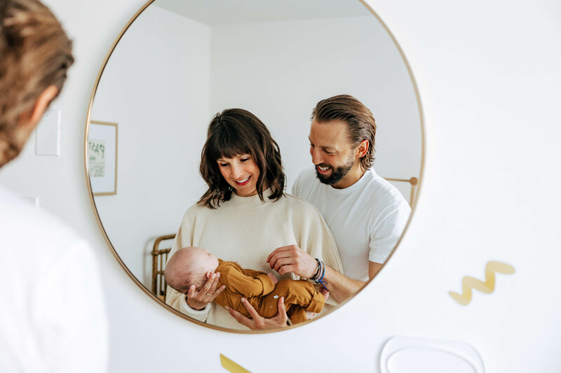 Parents Holding Newborn Reflected in Round Mirror