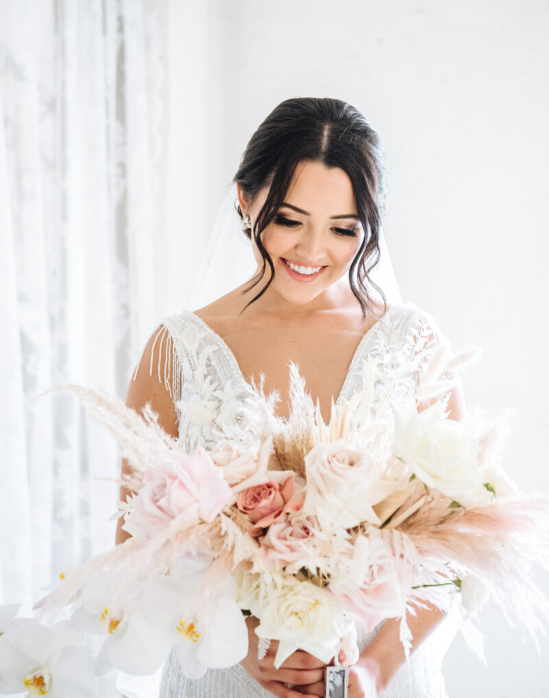 A photo of a happy bride looking down at her wedding bouquet