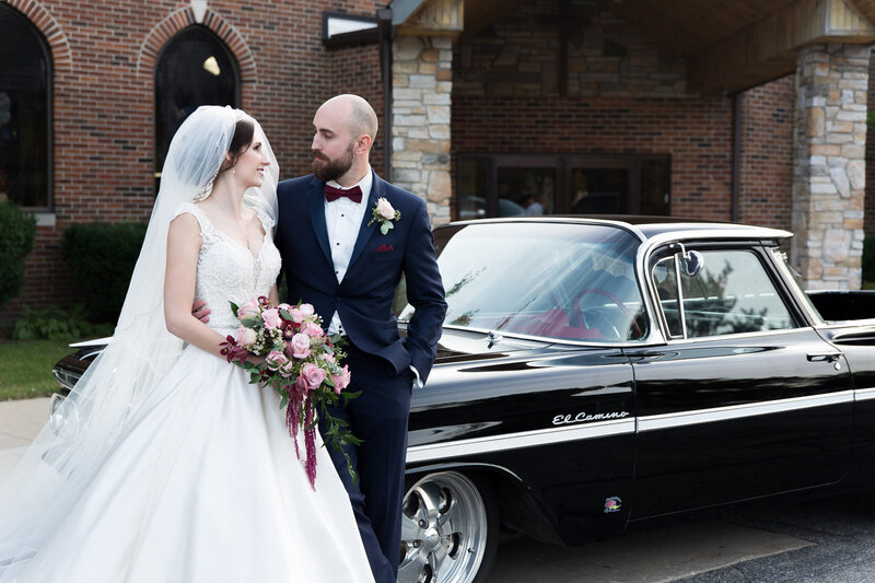 bride and groom in front of vintage car on wedding day
