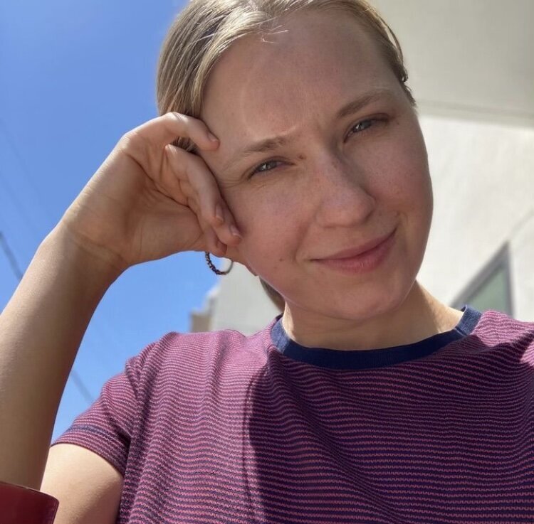 image of Krista Walsh sitting at outdoor table with coffee and laptop