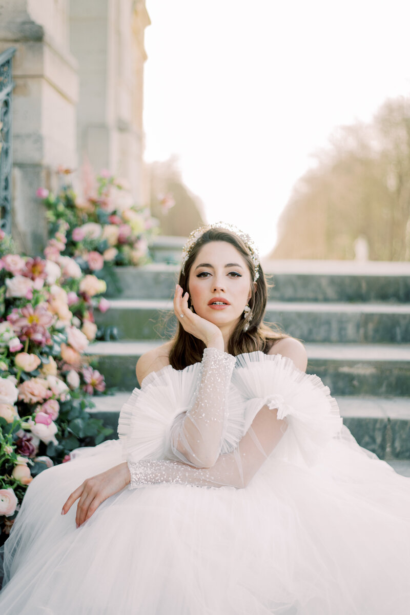 Bride in france holding her face with florals everywhere