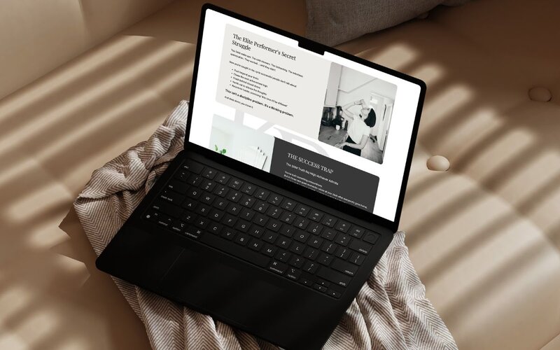 Open laptop resting on a beige couch, displaying a website with a black-and-white photo of kaya ramjee drinking a protein shake and text about elite performers' struggles and success traps.