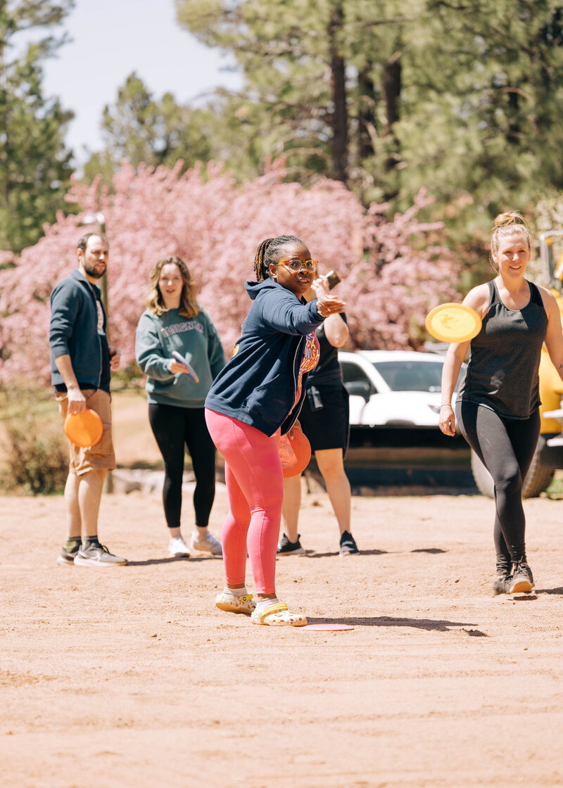 A group of friends play disc golf in a high desert landscape.