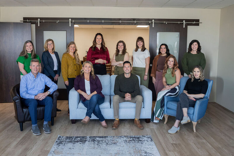 Group of men and women seated and standing smiling 