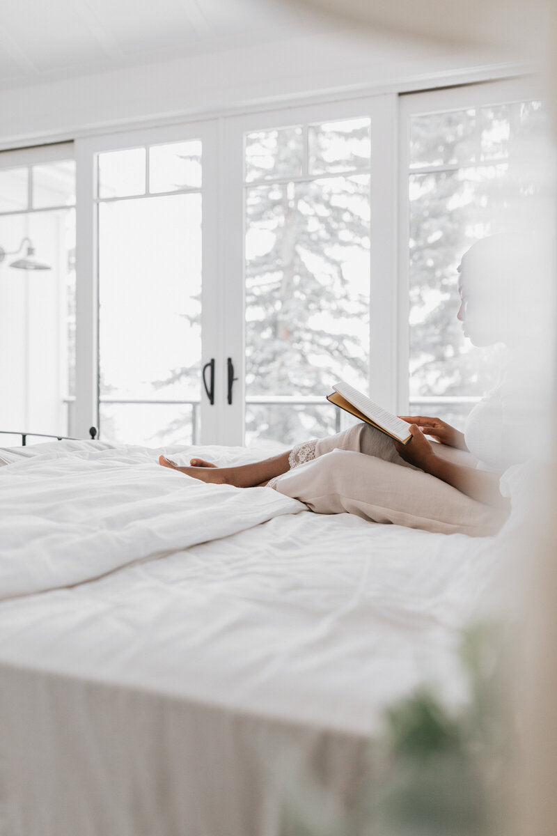 image of a black woman sitting on her bed on a website for online coaching program for moms of color in early motherhood