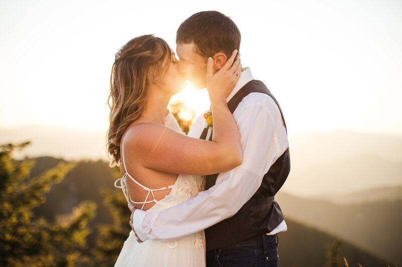 bride and groom kissing on mountaintop after elopement