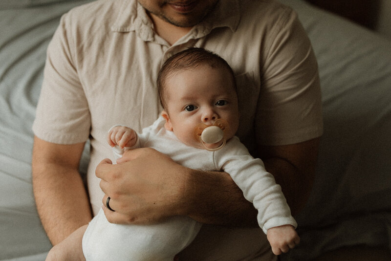Close-up of newborn's face cradled in dad's arms.