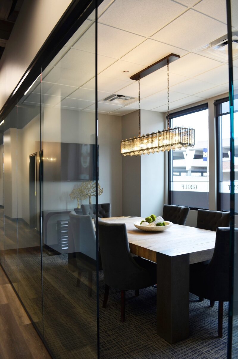 Conference room with dark chairs, a light table and large glass walls.