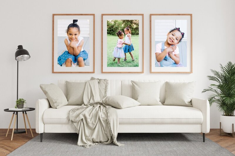 Wall gallery of two girls in wooden frames above neutral sofa.