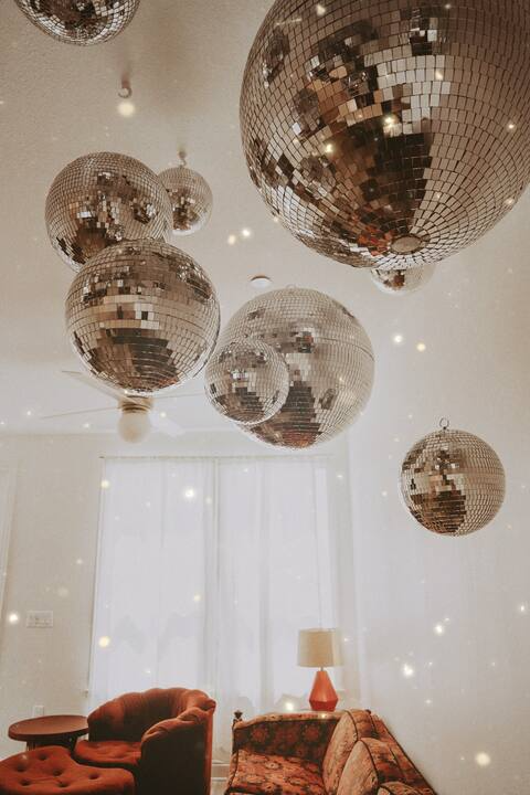 Cluster of disco balls hanging over the retro-inspired living area at Groovy Shack, a standout Panama City Beach stay near Santa Rosa Beach and Destin.