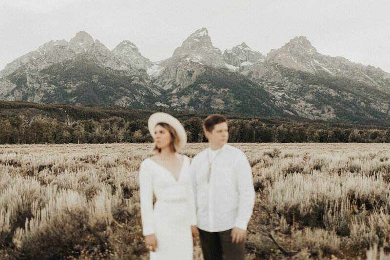 Bride and groom holding hands with mountains in focus