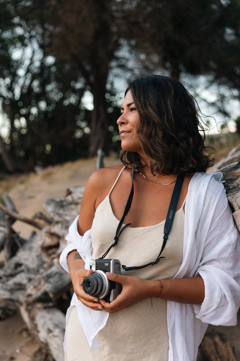 Amber is on the beach in Hawaii, holding an instant camera in her hands as she stares dreamily into the sunset (not pictured).