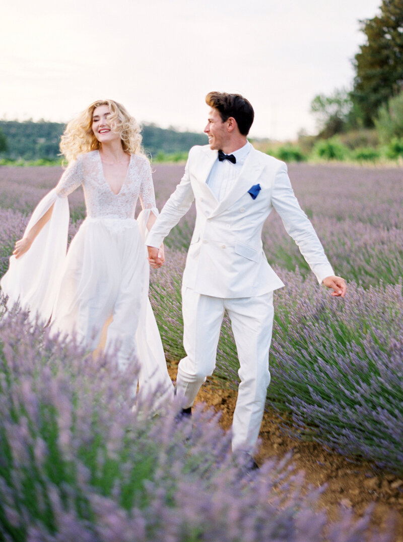 Groom leads his bride running through lavender fields
