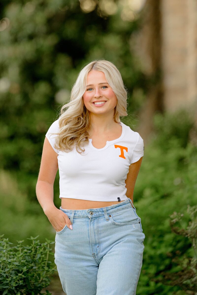 blonde charlotte, nc senior poses with one hand in her pocket wearing jeans and her future UT college crop top