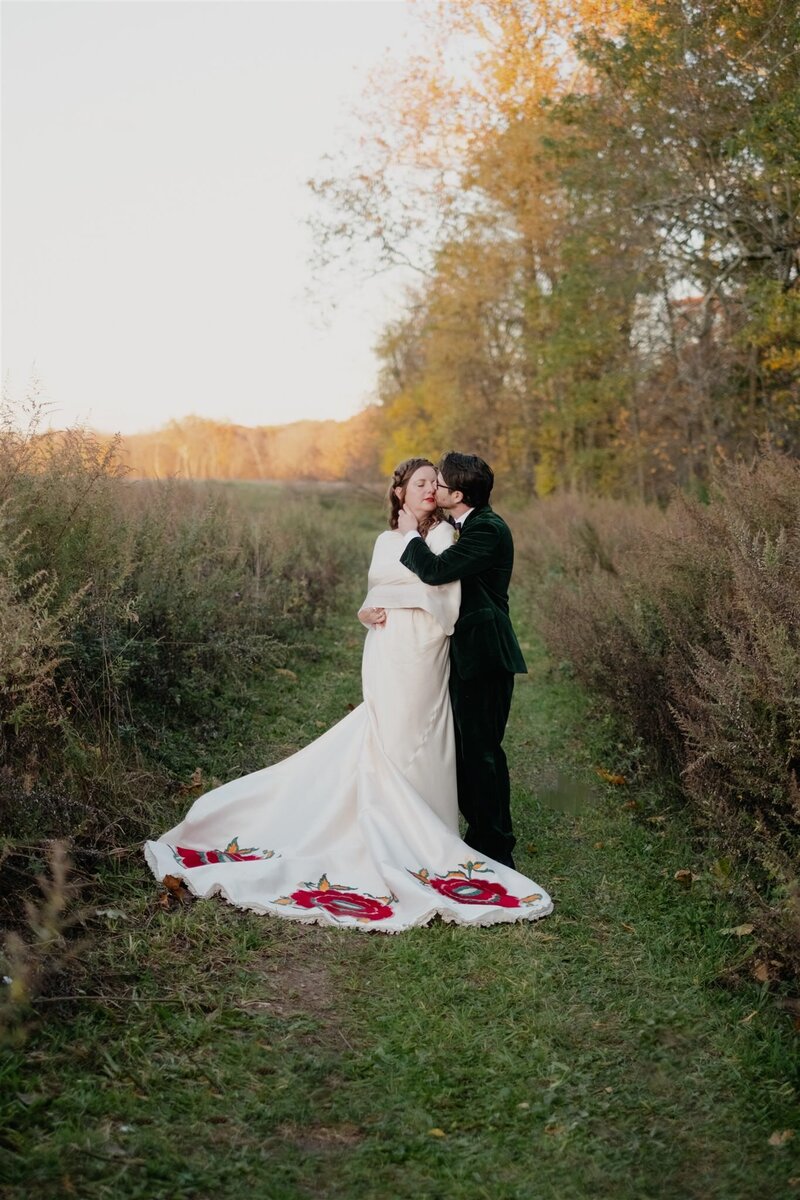 Hudson Valley wedding portrait of bride and groom embracing  on a grassy path surrounded by trees.