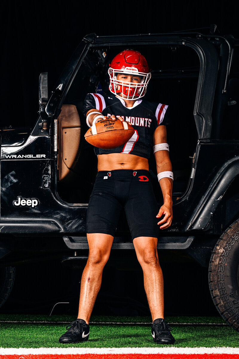 a dalton football player poses with his jeep during a photo shoot