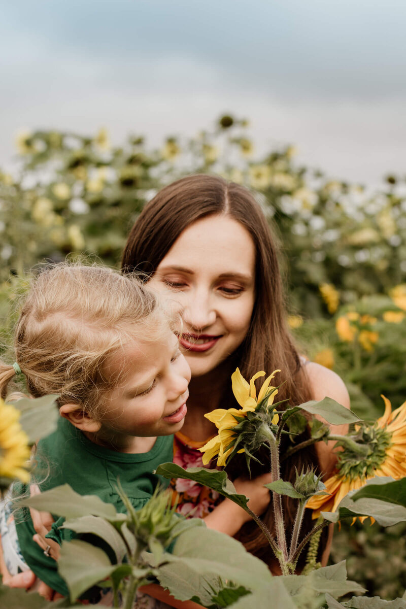 child with mom smelling a flower