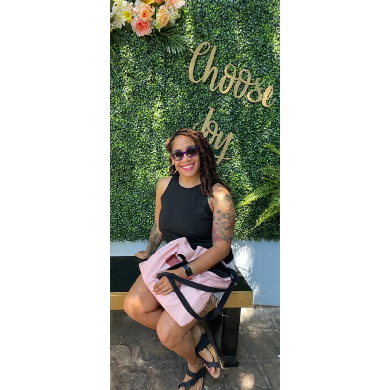 Vanessa Sujey seated, smiling, in front of a 'Choose Joy' sign. Text describes her as a speaker and life coach emphasizing holistic mental health.