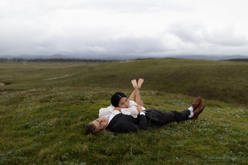 Bride and groom lying in tall grass, captured during an intimate Utah elopement by a wedding photographer.