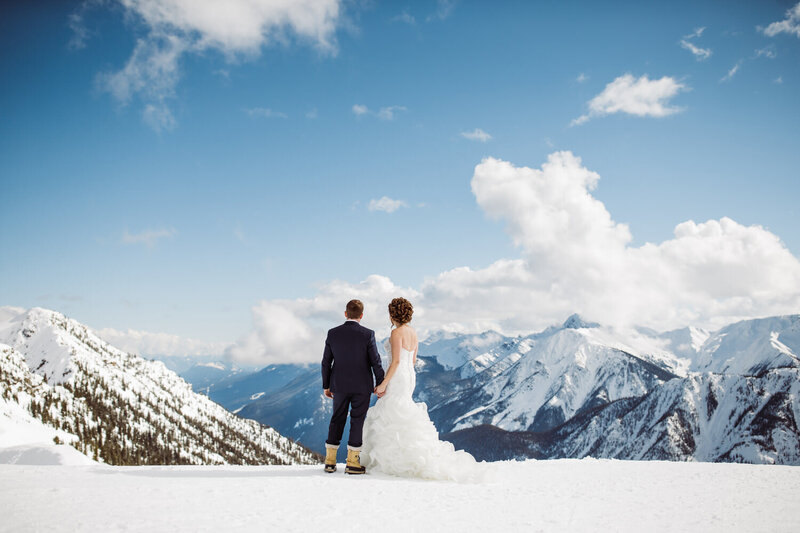 A stunning wedding photograph of a bride and groom together at Kicking Horse Mountain Resort in Golden, BC, with breathtaking mountain views surrounding them.