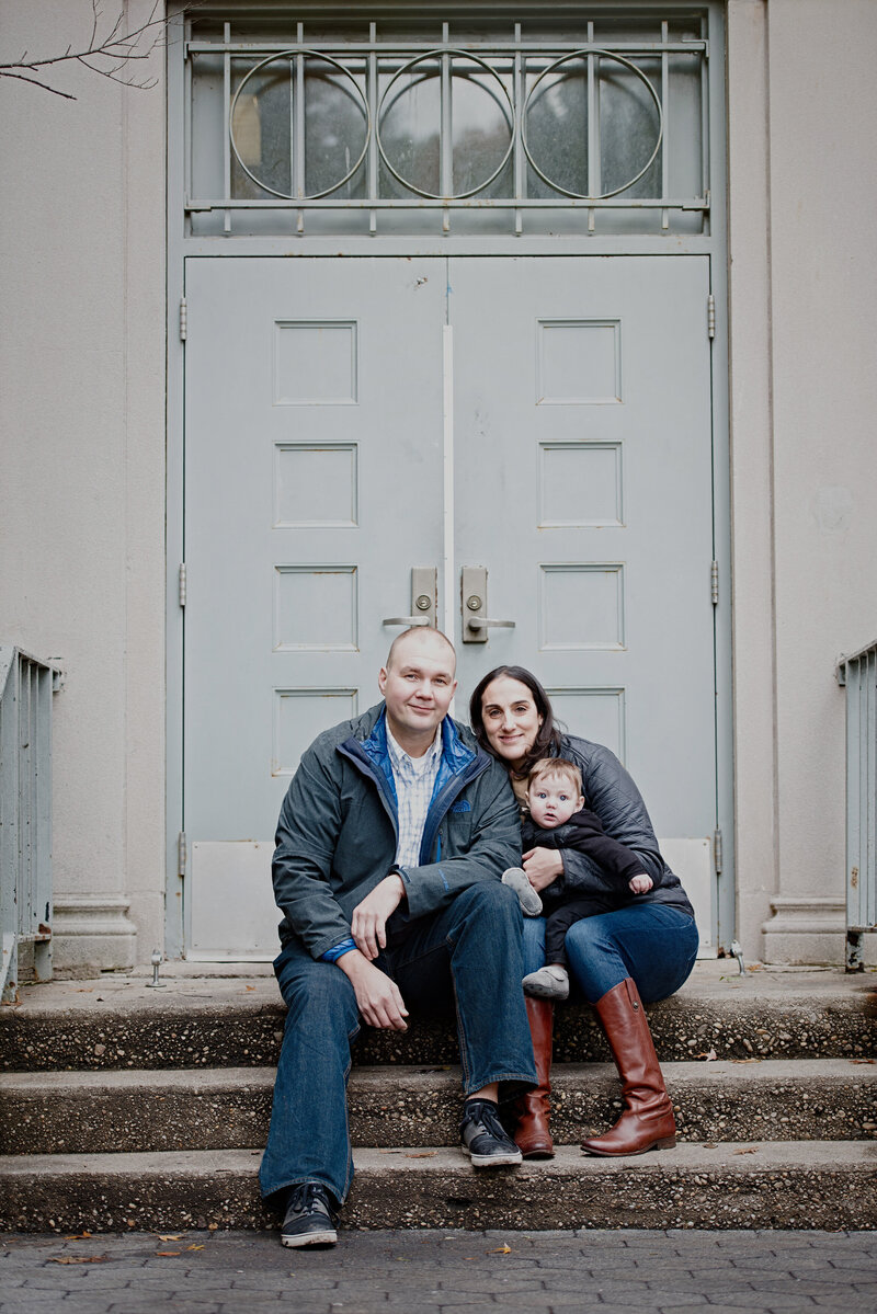 Two parents sitting on steps holding a small child