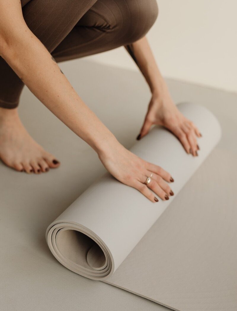 Image of a lady rolling up her yoga mat after a class