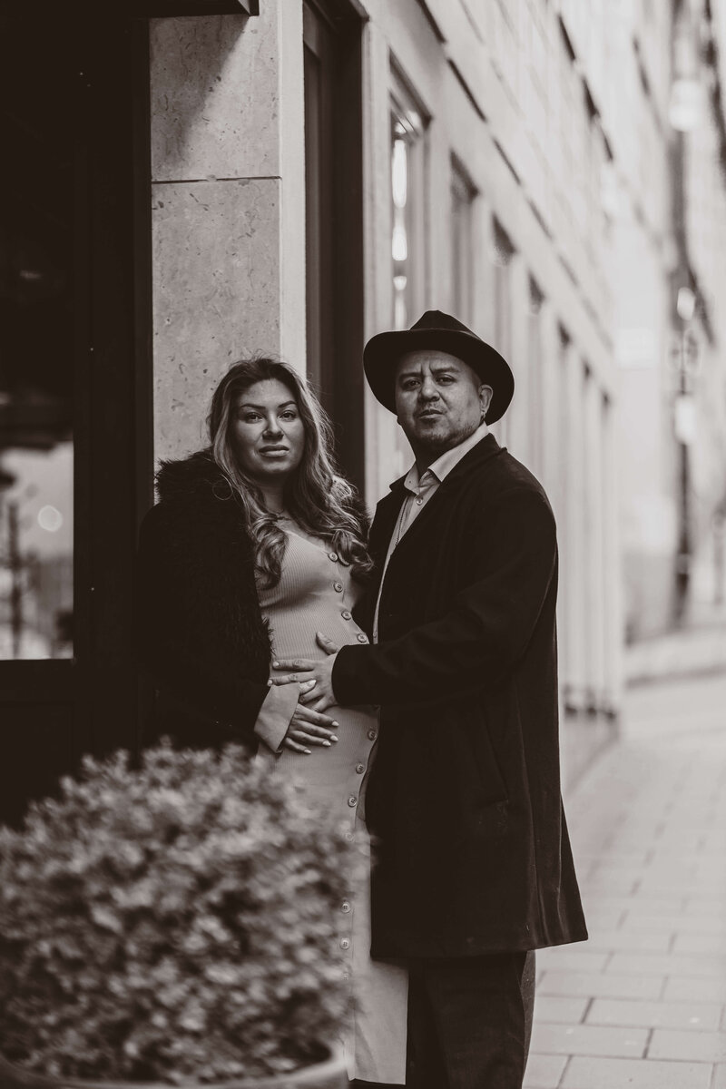 En gravid kvinna blir omhållen av sin partner under en gravidfotografering i Stockholm