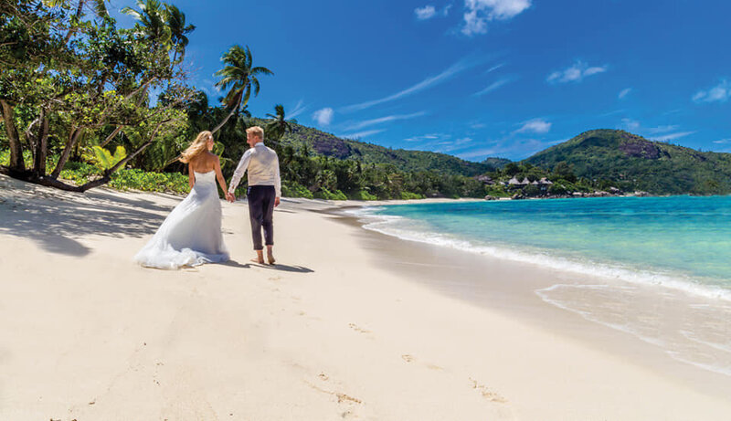 Bride and groom on a palm fringed beach.