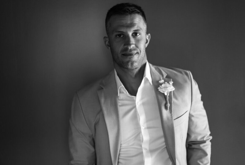 Black and white solo portrait of groom looking at the camera