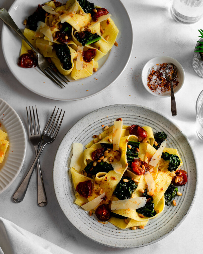 plates of papadelle pasta with kale and cherry tomates