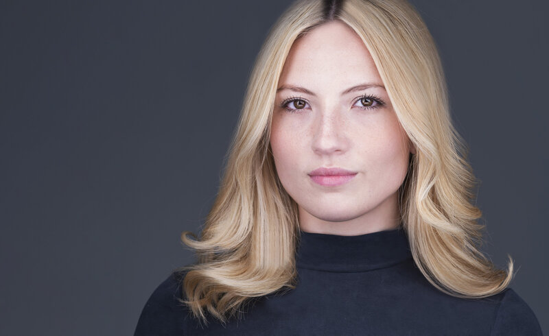 Woman with long blonde hair is looking at the camera with a closed mouth smile. Captured by Philadelphia, PA headshot photographer Liza Nicole.