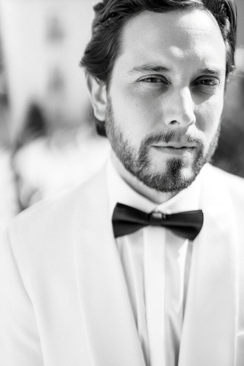 Black and white close-up portrait of groom in white tuxedo taken by a Toronto wedding photographer