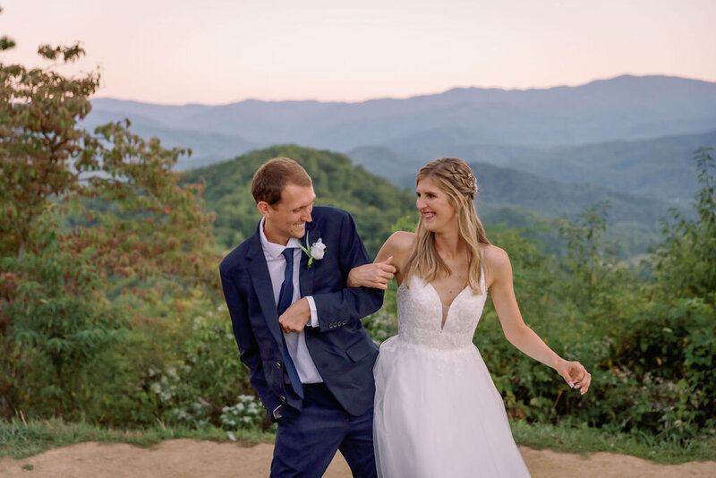 candid Smoky Mountain elopement photo of bride and groom with interlocked arms and laughing with one another