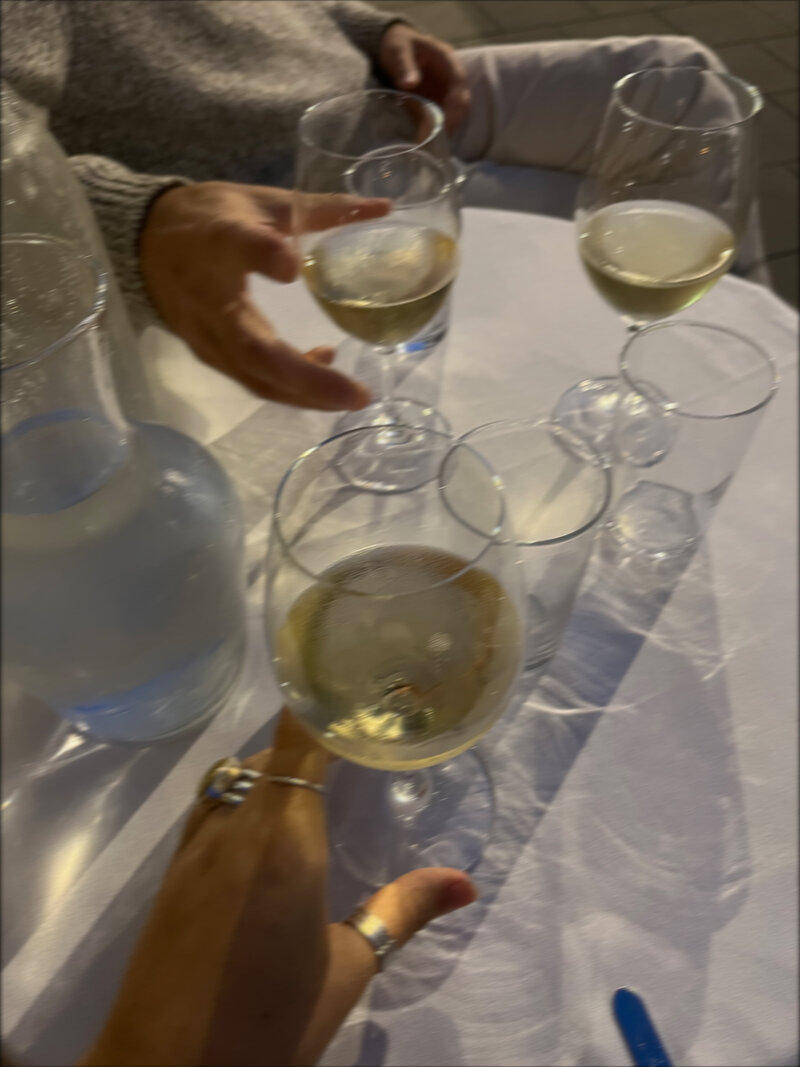 Friends hold their drinks on a white tablecloth