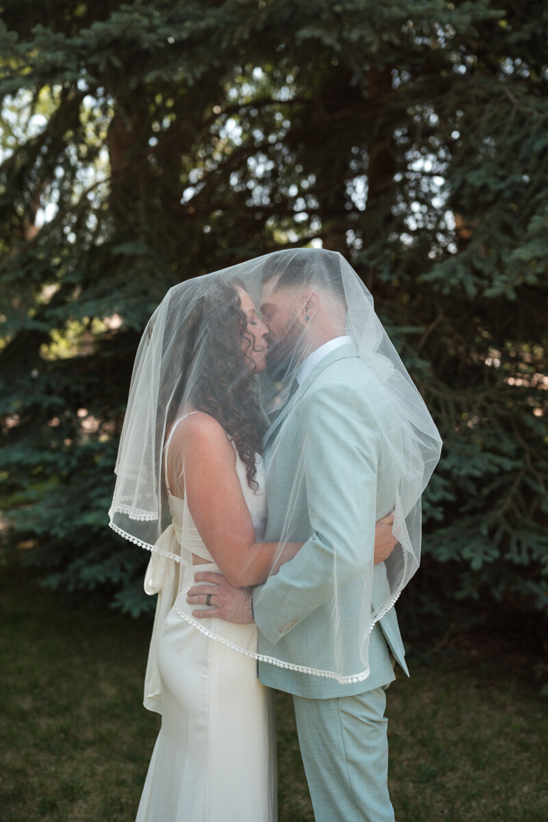 Black and white close-up of a groom holding the bride, with veil detail