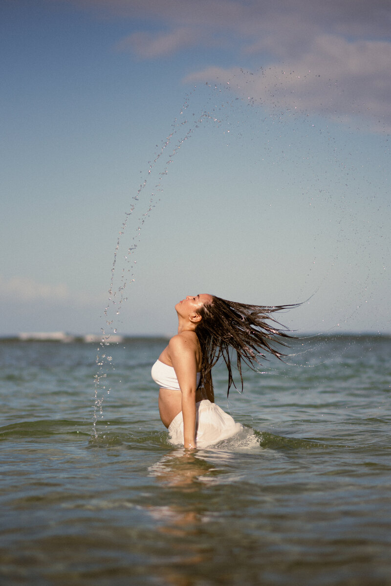 Woman posing on the beach for maternity portraits in Oahu, Hawaii