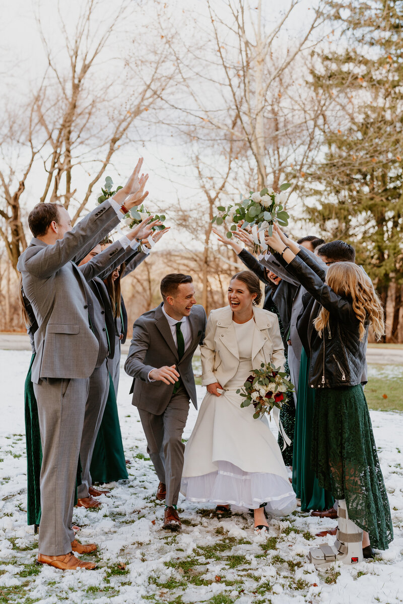 bride and groom surrounded by bridal party with raised hands