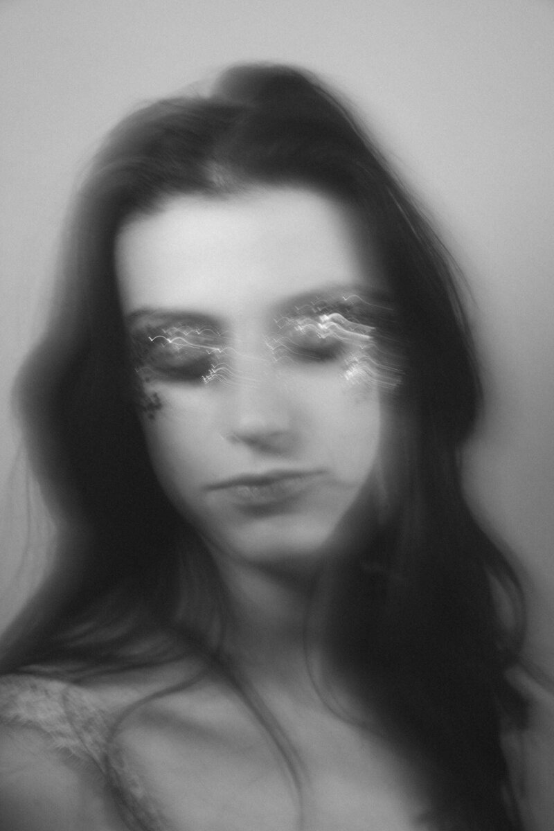 Portrait en flou artistique d'une jeune femme portant des paillettes sur les paupières lors de sa séance photo portrait à domicile à Lyon