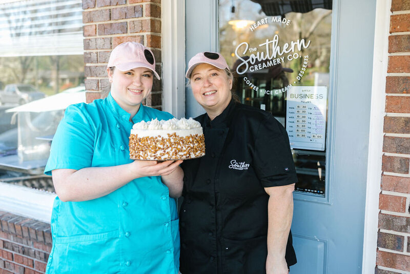 photo of two women holding a cake
