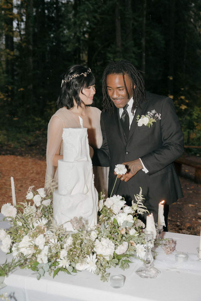 Couple cutting their wedding cake in an outdoor forest setting