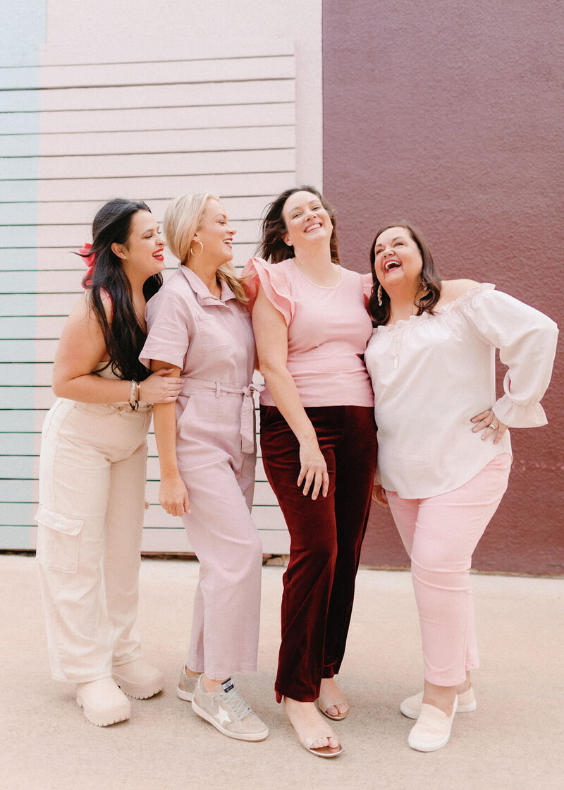 The Tallest Tulip team in coordinating light pink outfits standing next to each other and laughing