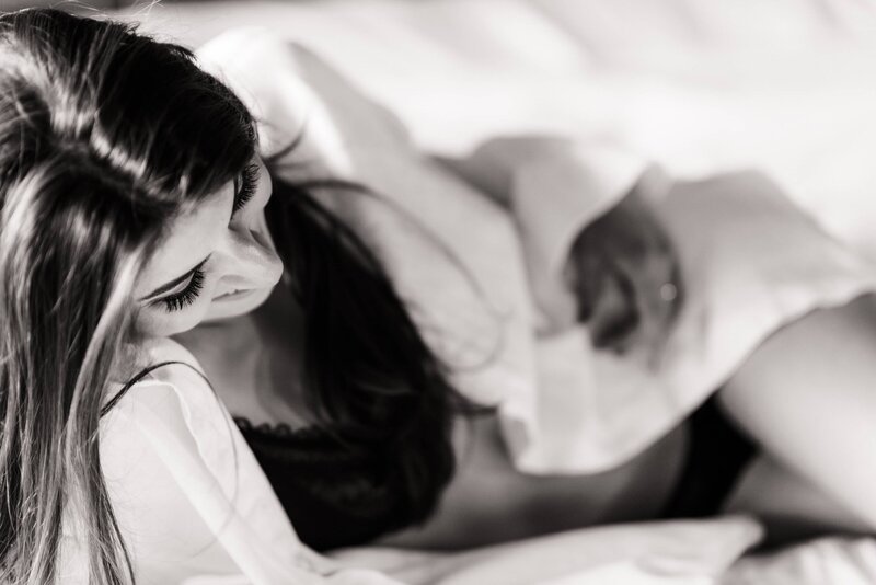 Photo of a bride laying on a bed playing with her hair and smiling