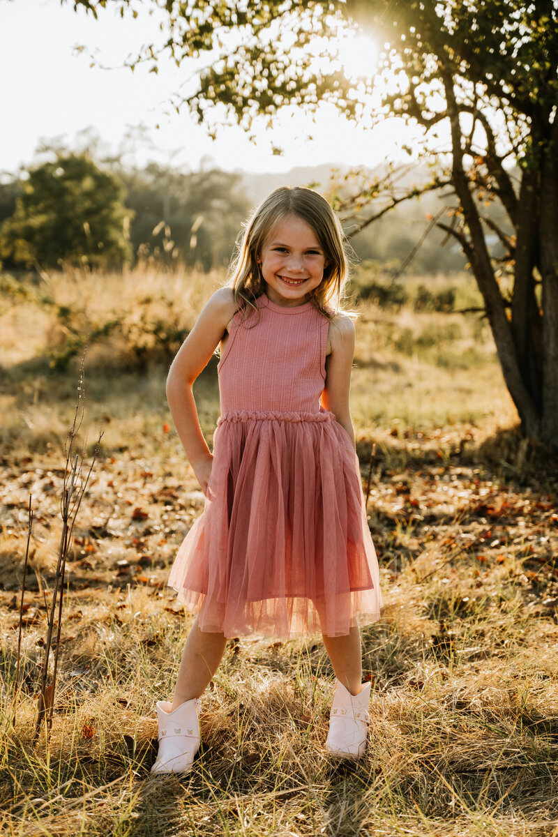 Girl strikes a pose at family session in pink dress at Park in Loomis. 