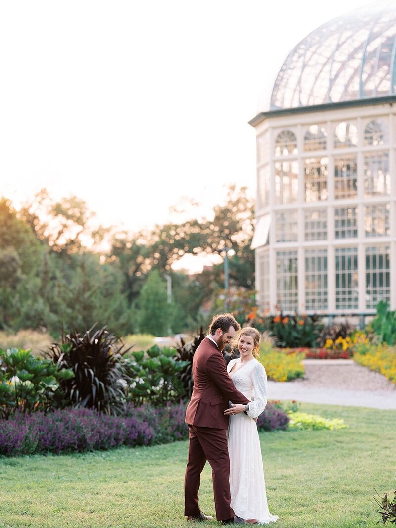 Bride and groom laughing and embracing in the gardens at Rawlings Conservatory