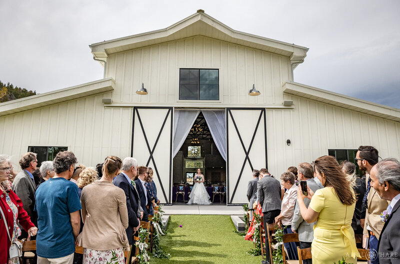 Bride Stands in the Open Barn Doors at The Woodlands Wedding Venue Before Walking Down the Aisle on her Wedding Day