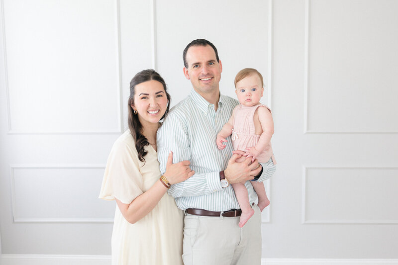 Portrait of a family of three snuggling together and smiling in a bright, beautiful Louisville Kentucky family photography studio taken by Missy Marshall
