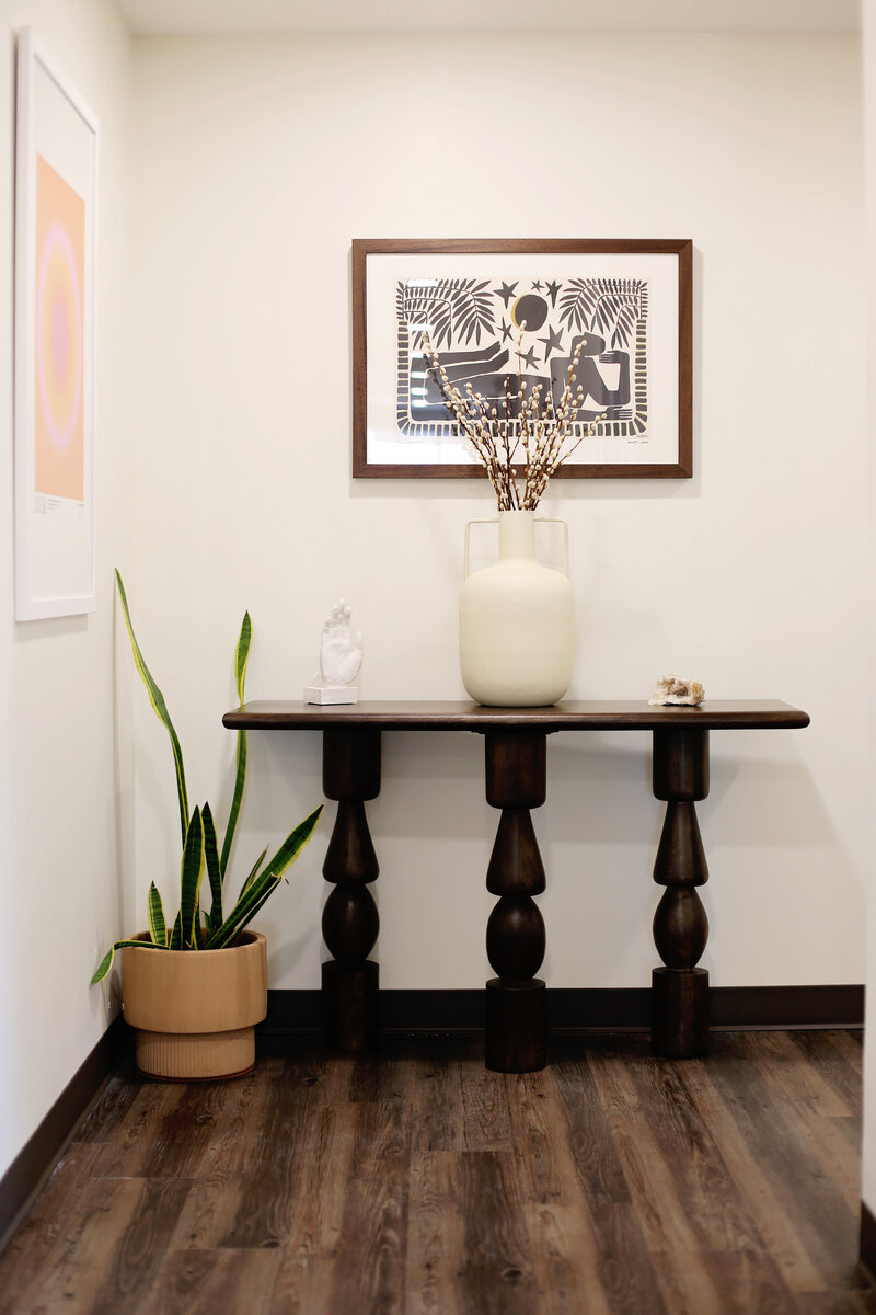 Minimal entry table with artwork and greenery at The Hive wellness studio