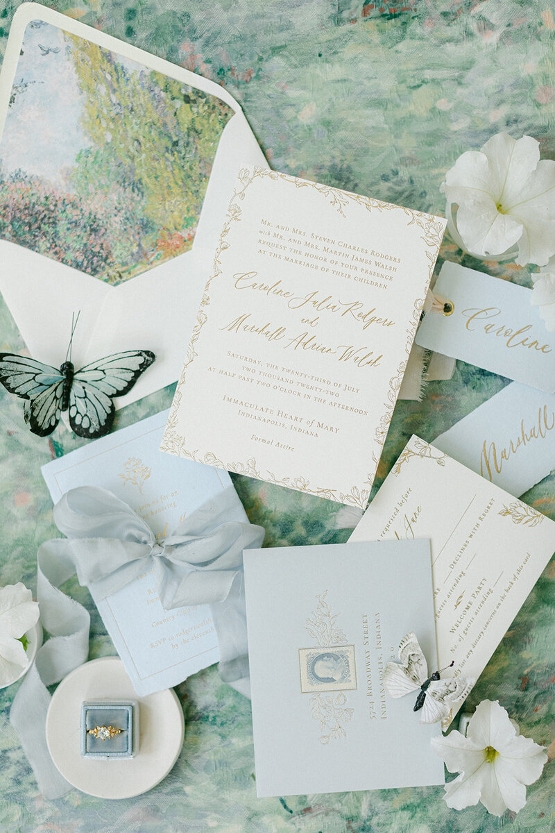 Soft blue linen flat lay mat styled with romantic paper goods and silk ribbon