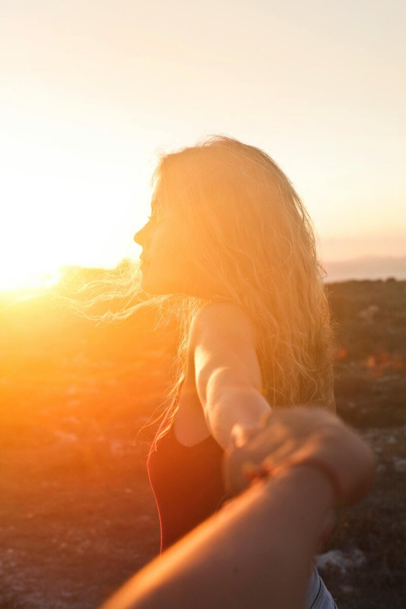Blonde woman with a sunset in the background.